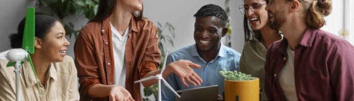 Cinco jovens de etnias diversas em uma reunião descontraída, rindo e discutindo ideias sustentáveis. Representam a Geração Z no trabalho.